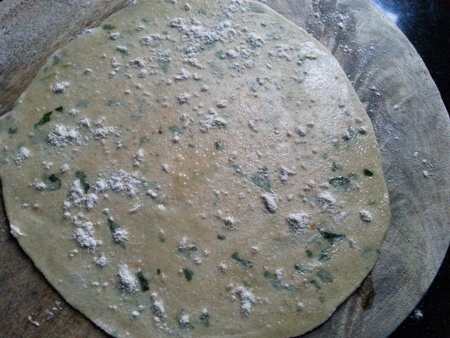 Apply butter and dust flour on rolled out mint stuffed paratha