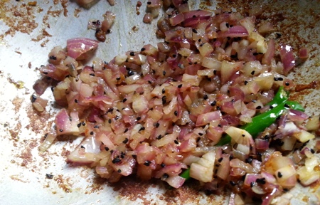 Fry chopped onions for traditional prawn recipe