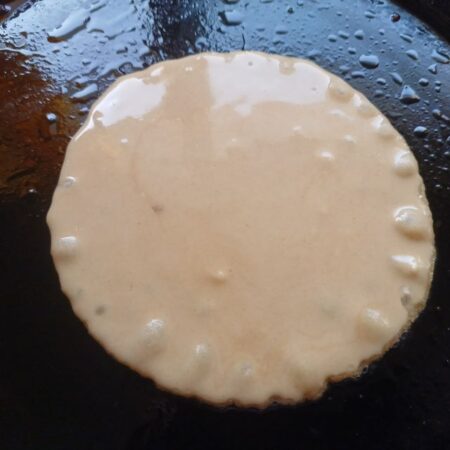 Pour a ladleful of bellam dosa batter onto a tava