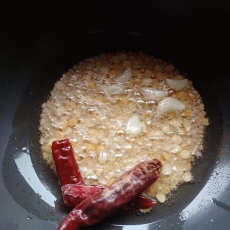 Dry red chillies and garlic cloves added to hot oil