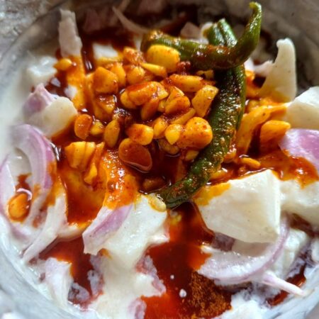 Pour the Nepali Chukauni tempering over the potato yogurt mixture